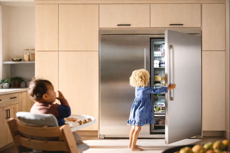 Child opening Electrolux EI33AF80WS freezer door in modern kitchen for DIY alignment check