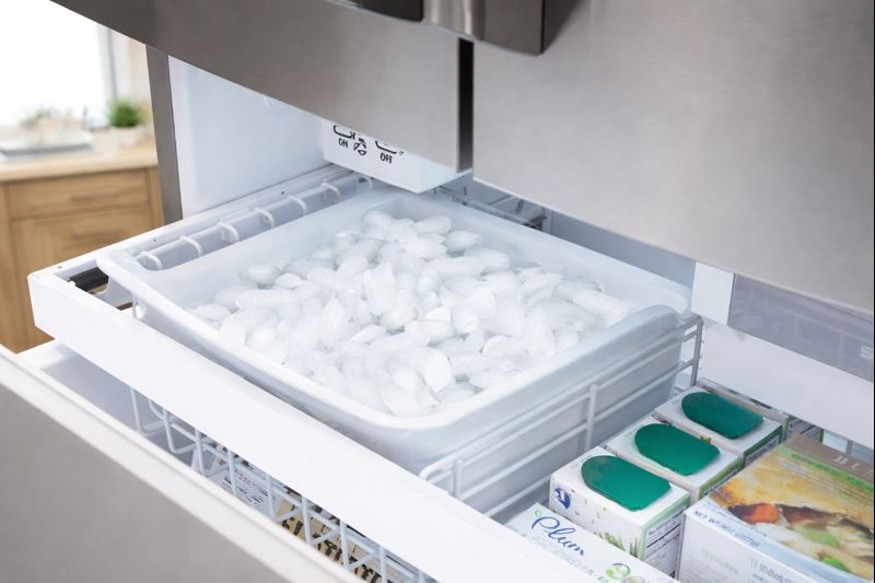 Open Electrolux EW28BS85KS bottom freezer drawer showing full ice bin and stocked frozen foods