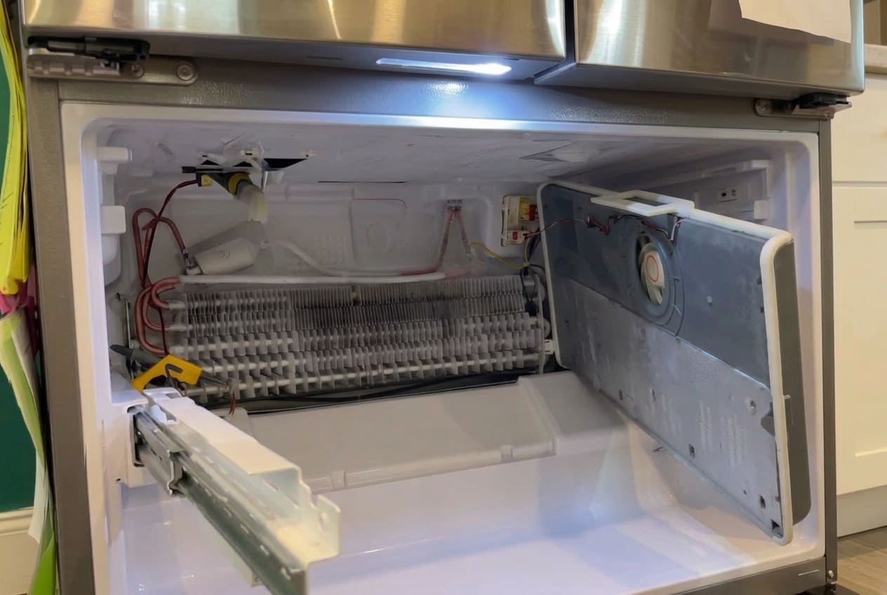 Technician checking Bosch refrigerator fan noise behind rear panel 