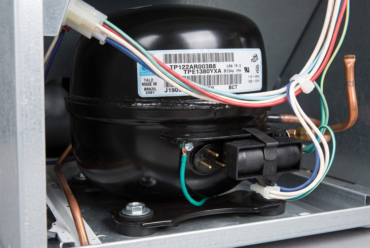 Amana refrigerator compressor motor close-up showing electrical terminals and start relay