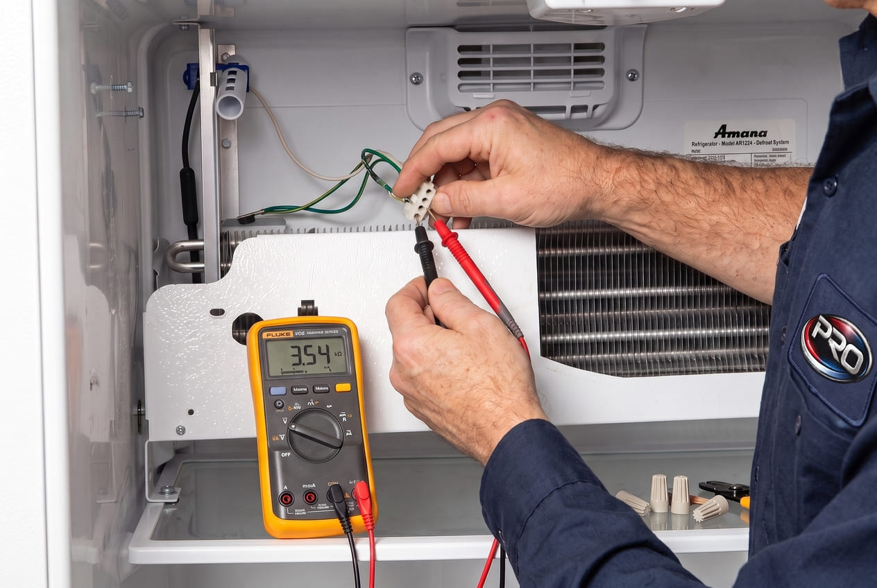Amana refrigerator thermostat component being tested with multimeter by appliance repair technician Atlanta 