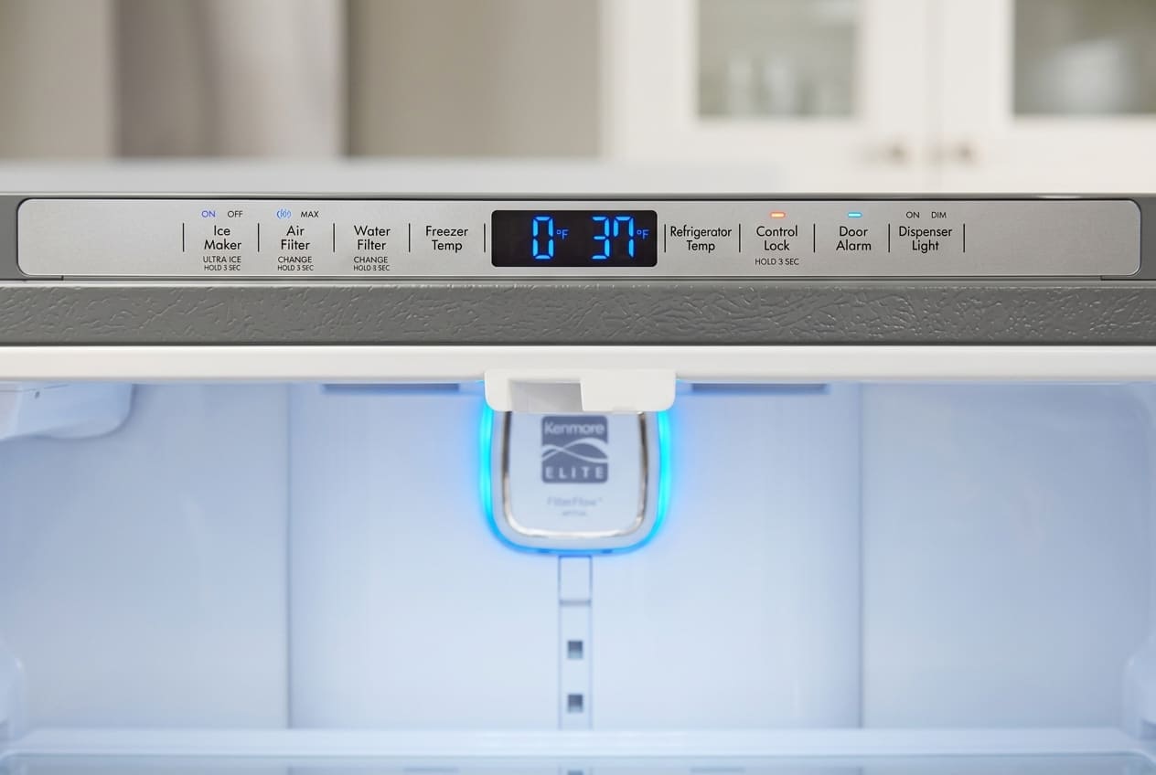 Close-up of Kenmore Elite refrigerator control panel with digital display showing freezer temperature at 0°F, featuring buttons for Ice Maker, Water Filter, Door Alarm and other settings.